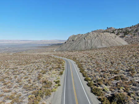 Aerial view of asphalt road in the middle of dusty dry desert land in Lee Vining, Mono County,...