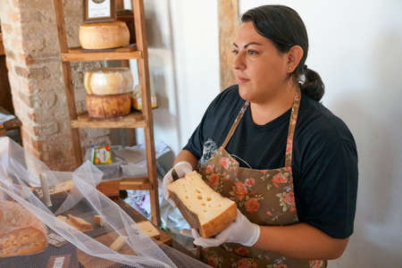 Vendor serving variety of traditional cheese in a cheese farm store, Fazenda Atalaia Cheese Farm, Amparo, State of Sao Paulo, Brazil. October 3rd, 2020のeditorial素材