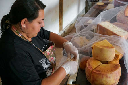 Vendor serving variety of traditional cheese in a cheese farm store, Fazenda Atalaia Cheese Farm,...