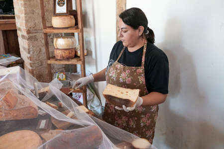 Vendor serving variety of traditional cheese in a cheese farm store, Fazenda Atalaia Cheese Farm,...