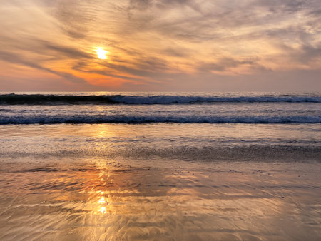 Colorful orange ocean beach sunset with deep clouded sky. Beautiful cloud over the sea during sunset.の写真素材