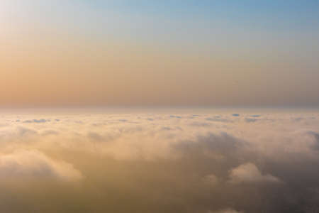Colorful aerial sunset view over the cloud facing the sun. Scenic view above the clouds
