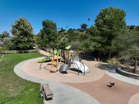 Colorful children playground activities in public park surrounded by green trees in San Diego,...