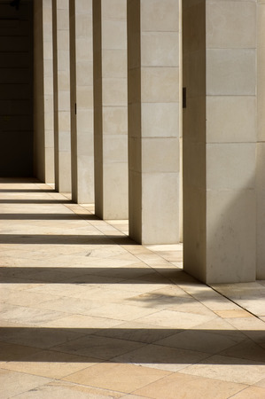 Stone columns lit from the side with long shadows cast upon the groundの写真素材