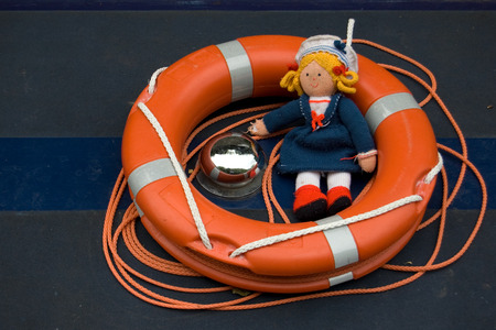 Orange lifebuoy and female rag doll with yellow hair dressed in a sailors uniformの写真素材
