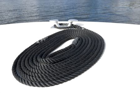 Black nylon mooring line or rope coiled on the deck at the bow of a boatの写真素材
