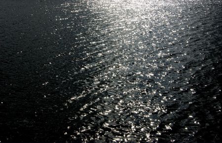 Glistening light catches the ripples of a calm stretch of waterの写真素材