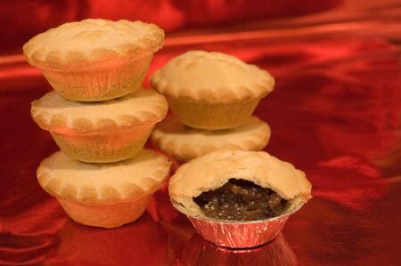 Mince or mincemeat pies traditionally eaten at Christmas against a warm red background の写真素材