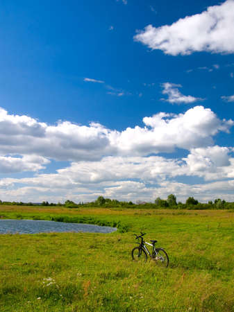 Scenic rural landscape with bicycle stood near pondの写真素材