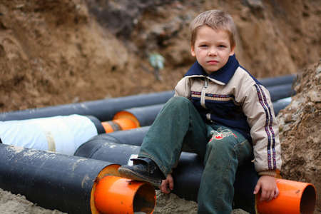 Child sits on a heating pipeの写真素材