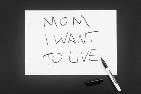 Written in black marker on a white piece of paper: Mom, I want to live. The concept of severe...