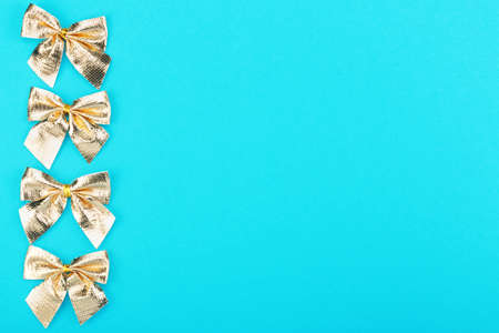 Golden christmas bows on blue background. Holidays mock-up with copy space for your design. Flat...