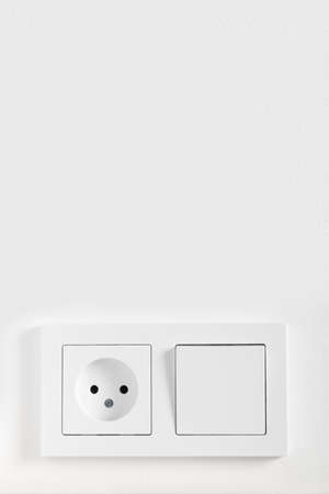 European electric light switch and socket on the painted white wall. Concept of home interior with...