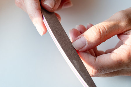 The girl does her own manicure at home. Girl's hands in the process of manicure close-up. Dust on the work area from the process. High quality photoの写真素材
