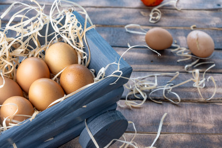 Fresh homemade chicken eggs, brown eggs on straw, eggs in a wooden container filled with straw on a...