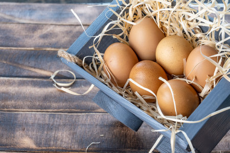 Fresh homemade chicken eggs. Brown eggs on straw. Eggs in a wooden container filled with straw. High quality photoの写真素材