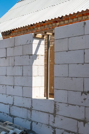 A built wall with a window opening made of white aerated concrete block, brick. Laying aerated concrete blocks. Construction of aerated concrete blocks, bricks. High quality photoの写真素材