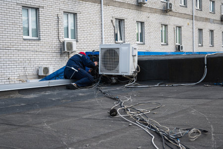 A master on the roof repairs the air conditioner. The master repairs the wires of the Internet on the roof. High quality photoの写真素材