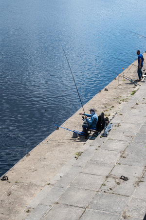 Fishermen on the concrete embankment of the city are fishing on the feeder. High quality photoの写真素材