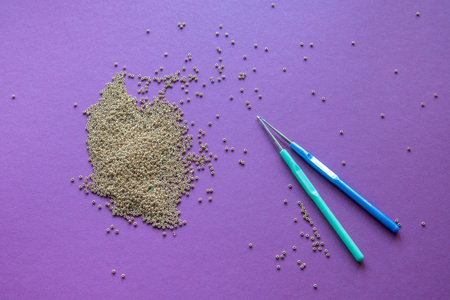 a bunch of gold beads, crochet hooks on a purple background. High quality photoの写真素材