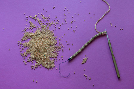 crochet beaded bracelet next to a bunch of gold beads on a purple background. High quality photoの写真素材