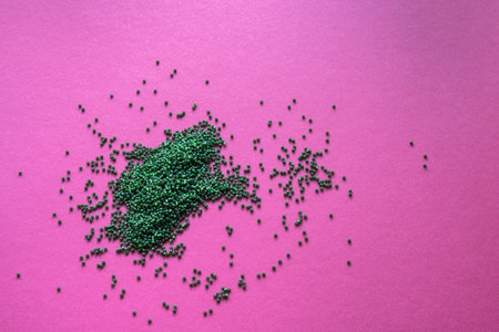 green beads poured into a pile on a purple background. High quality photoの写真素材