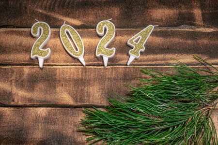 Beautiful Christmas background with the date 2024 on a wooden old table and fir branches. Happy New...