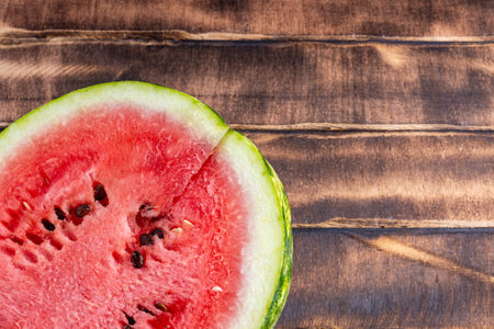 Half of a juicy watermelon on a wood background. Half of a watermelon on a cutting board close upの写真素材