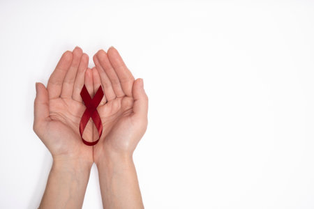 Woman holding red ribbon as symbol of World Cancer Day, on white background, breast cancer awareness...