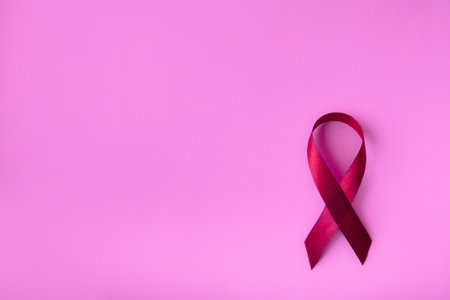 Red ribbon on a pink delicate background, top view with space for text. Campaign to help people...