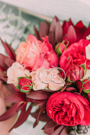 wedding rings on red roses on the bridal bouquetの写真素材