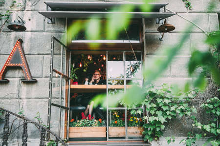 Young woman and man talking during first date in cozy coffee shop enjoying free time together,hipster girl checking notification on mobile while spending time with boyfriend having lovely conversationの写真素材
