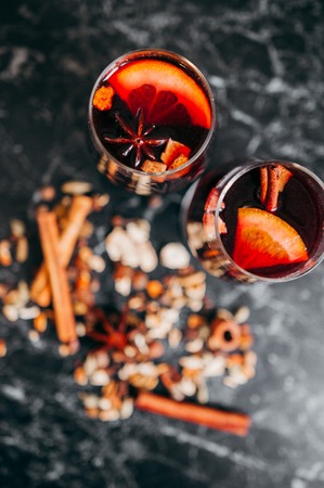 Christmas mulled red wine with spices and fruits on a wooden rustic table. Traditional hot drink.の写真素材