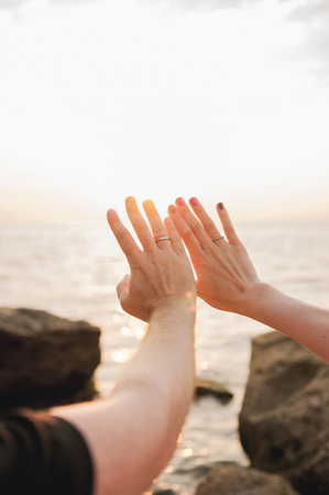 Young couple in love standing on the beach at the seaside enjoying romantic evening and watching sunset. Family have a rest on the beach in summer.の写真素材