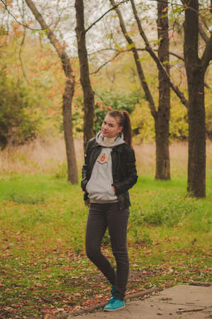 Girl in the park in autumn portrait on the background of trees.