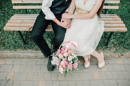 Young beautiful couple in love walks in the summer park. A girl in a bright dress with bright makeup. And her boyfriend in a suit with a red bow tie. Concept - the happiness of lovers and loveの写真素材