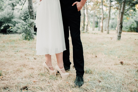 Young beautiful couple in love walks in the summer park. A girl in a bright dress with bright makeup. And her boyfriend in a suit with a red bow tie. Concept - the happiness of lovers and loveの写真素材