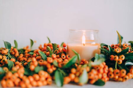 Sea buckthorn, autumn concept. Warm and comfortable home. Candles and coniferous branches.の写真素材