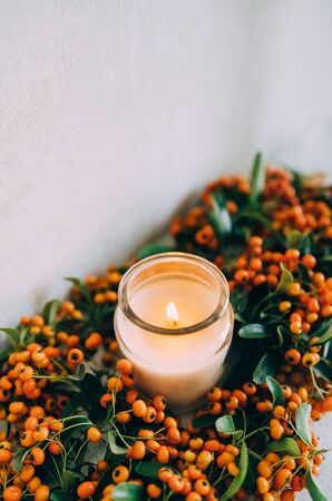Sea buckthorn, autumn concept. Warm and comfortable home. Candles and coniferous branches.の写真素材