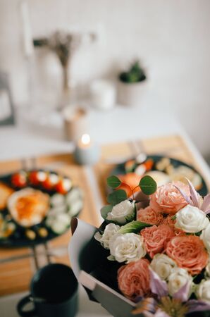 A beautiful bouquet of flowers in the foreground. A delicious breakfast in the background.の写真素材