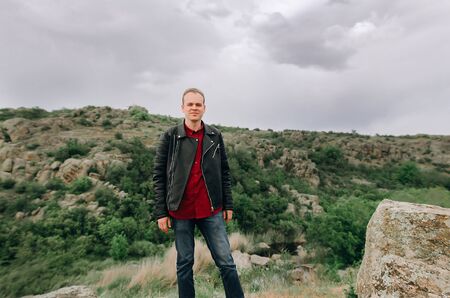 Young guy in nature. In the mountains of the canyon. Portrait of a man