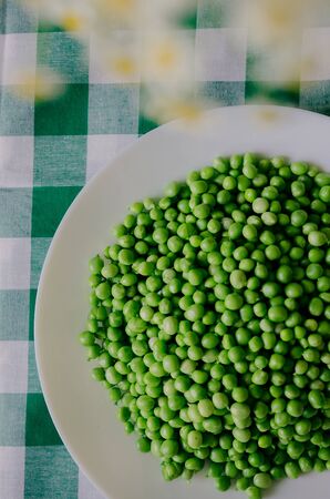 Green peas on a green tablecloth in the kitchenの写真素材