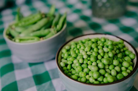 Green peas on a green tablecloth in the kitchenの写真素材