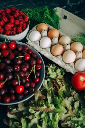 The concept is healthy food. Summer table from your garden. Berries, vegetables, eggs, greens.