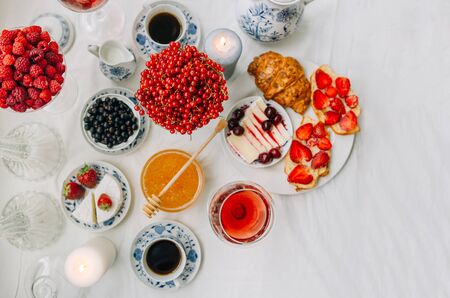 Breakfast at home, berries, coffee, honey, croissants, cheese. Beautiful serving and wooden spoon for honey.の写真素材