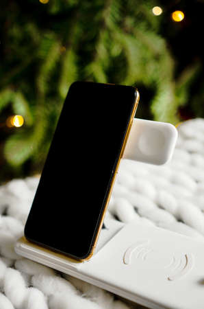 Convenient light white wireless charger for your phone and watch. In the photo, the phone is charging. Technologies of the 20th and 21st centuriesの写真素材