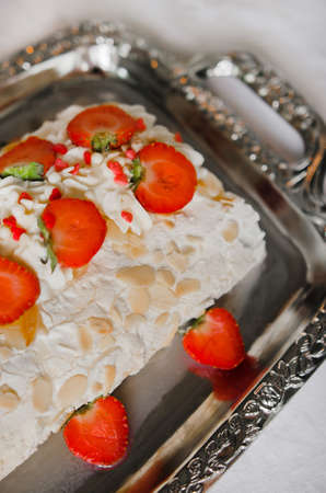 Meringue roll with almond flakes on a beautiful background. Summer Pavlova dessert with delicate...
