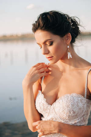 Close-up portrait of a brunette model girl in the role of a bride. Beautiful face, portrait at sunset in summer dayの写真素材
