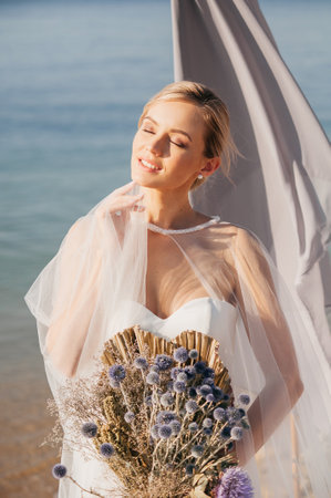 Stylish bride standing on a beautiful sea landscape in the morningの写真素材