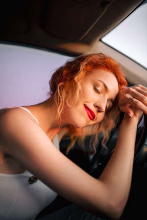 Pretty girl in a car at sunset